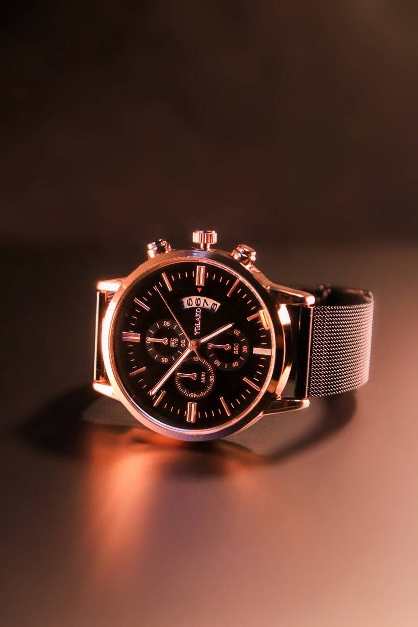 Montre Infinity dorée avec cadran noir sous un éclairage chaleureux. Un design luxueux et sophistiqué pour une touche d'élégance au quotidien.